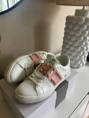 Valentino Garavani vita sneakers med nitar - Säljer ett par valentino skor då dom är för små för mig. Använt dom ett få tall gånger men dom är fortfarande fräscha förutom undersidan som är lite smutsig som man kan se på bilderna (har försökt å få bort allt smuts).