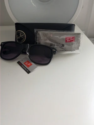 Svarta Ray-Ban solglasögon  - Klassiska svarta Ray-Ban med mörka glas och ikonisk form. Dem tintas så ljusare längre ner och mörkare upp säljer då jag behöver pengar. 