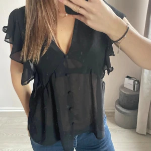 Svart blus  - Snygg svart blus i transparent material med volangdetaljer längs ärmar. Märket är SHEIN, köpt här på plick, men inte kommit till användning. I fint skick💕