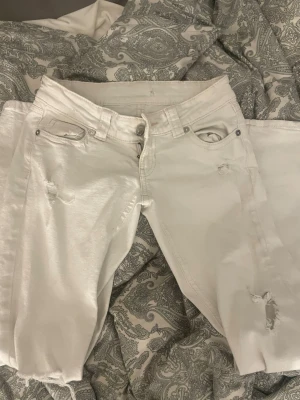 Vita low waist jeans från Gina tricot  - ett par snygga vita lowwaist jeans från Gina tricot som bara har använts några antal gånger som även har ett band i midjan som jag har satt på 