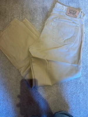 Beige Levi's jeans 517 w33 L32 - Snygga beige jeans från Levi's med klassisk femficksdesign och rak passform. Jeansen har Levi's ikoniska läderpatch bak i midjan och är tillverkade i bomull. Perfekta för en avslappnad och stilren look.