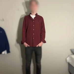 Vinröd skjorta från Polo Ralph Lauren - Säljer en snygg vinröd skjorta från Polo Ralph Lauren i storlek M (modellen är 188 cm lång och väger 70kg). Den är mycket bra skick och har inga defekter (skick 8/10). 100% bomull