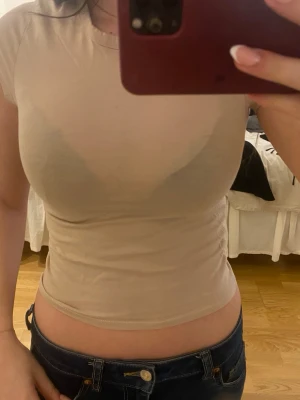 Beige tight t-shirt i bomull - Säljer en enkel och stilren beige t-shirt i mjuk bomull. Modellen är tight och har korta ärmar samt rund halsringning. Perfekt basplagg att matcha med jeans eller kjol.