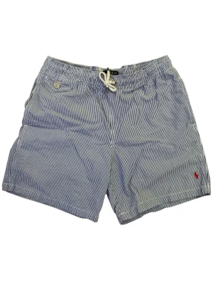 Randiga badbyxor från Polo Ralph Lauren - Snygga badbyxor från Polo Ralph Lauren med smala blå och vita ränder, dragsko i midjan och liten röd logga broderad framtill. Klassisk modell med fickor och bakficka med knapp. Perfekta för stranden eller poolen. Hör av er vid fler frågor eller funderingar pris kan diskuteras.