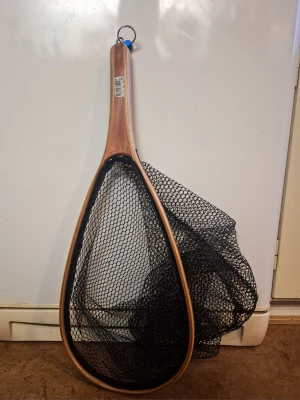 Fiskhåv med träram och svart gummi nät - Säljer en fiskhåv med robust träram och svart nät. Handtaget har en metallring för enkel upphängning. Perfekt för fiskeutflykter och enkel att bära med sig. Nätet är rymligt och ramen har en snygg träfinish.