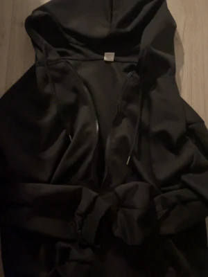 Svart zip hoodie  - En svart hoodie med dragkedja framtill och Luva.  Perfekt för en chill och avslappnad stil. Materialet känns mjukt och bekvämt. 