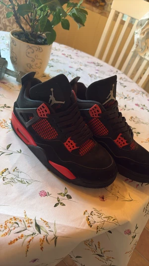 Svarta och röda Air Jordan 4 sneakers - Säljer ett par Air Jordan 4 sneakers i svart och rött inte äkta beställda från pandabuy nån liten fläck som säkert går bort men har inte testat storlek 41