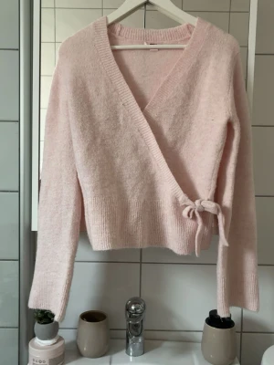 Rosa stickad tröja - Söt ljusrosa stickad omlottkofta med knytband i sidan. Koftan är sjukt söt och är i 170 ifrån gina