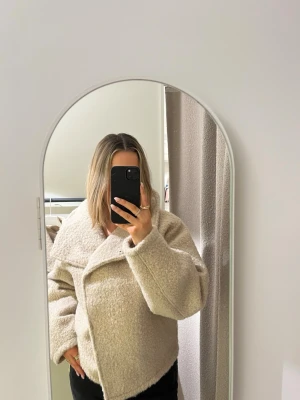 Beige teddyjacka med oversized krage - Säljer en supermjuk och fluffig beige teddyjacka med oversized krage och avslappnad passform. Jackan har en modern look och är perfekt för dig som gillar trendiga ytterplagg. Materialet är teddy/fuskpäls som ger en mysig känsla och cool stil. Knappt använd från gina. Passar dig som har S,M och L i storlek. 