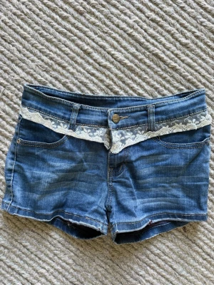 Låg missade jeansshorts med spets - Riktigt snygga lågmidjade jeansshorts med spetsdetaljer både fram och på fickan där bak. Perfekt nu för sommaren! Kan sänka pris vid snabb affär.