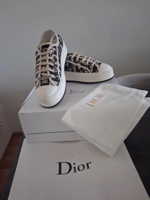 Walk’n’Dior  Christian Dior platform sneakers - Säljer ett par snygga Dior Oblique sneakers i lågt utförande. Skorna har en beige och marinblå monogramdesign, vita snören och robust vit sula. Tillverkade i canvas med klassisk Dior-logga på sidan och tungan. Perfekta för dig som vill sticka ut med lyxig streetstyle.
