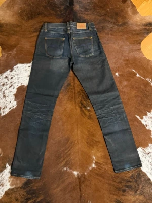 Nudie BigBengt NightThunder - Tjena! Säljer dessa riktigt snygga nudie jeansen ifrån tidigt 2010tal, fint skick 9/10, modellen är BigBengt NightThunder och sitter straight, på sista bilden ser du passform(inte samma par men exakt samma modell), hör av dig vid funderingar!🙌