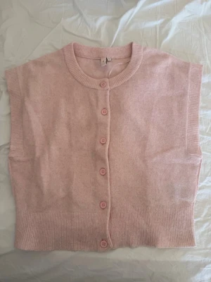 Ljusrosa stickad väst från Nelly - Supersöt ljusrosa stickad väst från Nelly med rund halsringning och knappar framtill. Perfekt att slänga över en t-shirt eller skjorta för en chill och trendig look. Västen har ribbade kanter och är riktigt mjuk och skön. Endast använd ett fåtal gånger, så ser nästan ut som ny! Skicka pm ifall ni har fler frågor eller vill ha fler bilder!💕