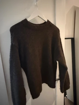 Brun stickad tröja från Gina Tricot - Mysig brun stickad tröja från Gina Tricot i storlek XS. Tröjan har rund halsringning, lång ärm och är gjord i ett mjukt, fluffigt material som passar perfekt för kyligare dagar.