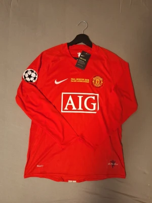 Manchester United tröja 07/08 Ronaldo #7  -  Lag: Manchester United. Spelare: Ronaldo #7. Turnering: Champions League Final 2008 (Moskva). Ärm:Långärmad. Badge: Champions League badge på armen  Denna tröja är från Champions League-finalen 2008 i Moskva där Manchester United mötte Chelsea i en av de mest minnesvärda finalerna genom tiderna. Matchen gick till straffar där United stod som vinnare, och Cristiano Ronaldo gjorde mål i matchen. Tröjan har finaltryck på bröstet samt Champions League badge på armen.