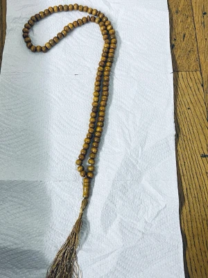 Brunt misabaha med träpärlor och tofs - Säljer ett långt misabaha med runda bruna träpärlor och en dekorativ tofs i bronsfärgad tråd. Misabaha har en enkel och naturlig look, perfekt för dig som gillar boho-stil eller vill ha något unikt till din outfit.