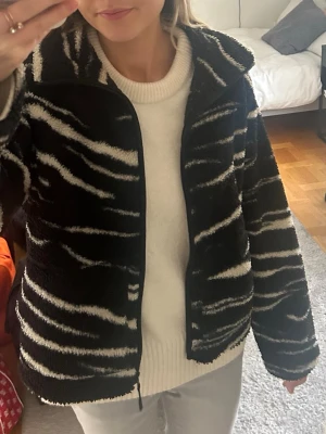 Svart teddyjacka med zebramönster - Säljer en svart teddyjacka med vitt zebramönster. Verkligen jättecool. Storlek M och inte jättevarm så den går att ha inomhus oxå som en fleecetröja om man vill. 