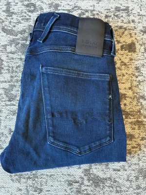 Mörkblå Replay Hyperflex jeans W31/l34 - ny utan prislapp - Snygga mörkblå jeans från Replay Hyperflex med klassisk femficksmodell och stretchigt material (Hyperflex model) för extra komfort. Jeansen har raka ben och en stilren look med diskreta sömmar och läderpatch bak i midjan. Storlek w31/l34. Kontakta mig vid frågor!