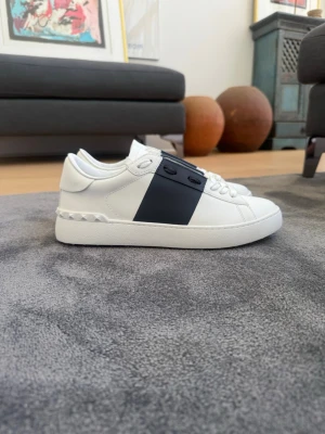 Valentino open  - Snygga vita sneakers från Valentino med en bred blå remsa över sidan och ikoniska nitar längs hälen. Kommer med box + dustbag!