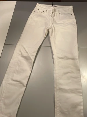 Vita raka jeans från Filippa K - Snygga vita jeans med rak passform och klassisk fyraficksdesign. Jeansen har bälteshällor och silverfärgade nitar. Perfekta för en fräsch och stilren look. Materialet är denim i bomull.