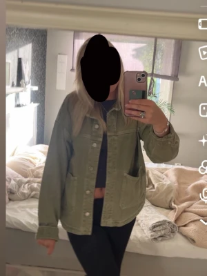 Olivgrön jeansjacka med stora fickor - Snygg olivgrön jeansjacka med raka linjer och stora framfickor. Jackan har klassisk krage, knäppning framtill och avslappnad passform. Perfekt för dig som gillar en cool och avslappnad stil.