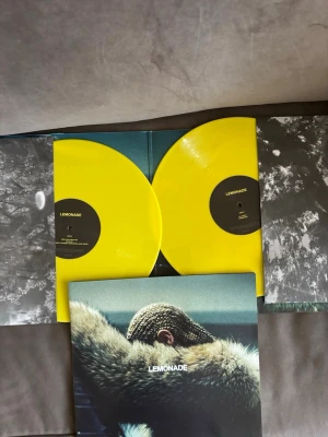 Beyonce Lemonade dubbel LP gul vinyl - Beyonce Dubbel LP med albumet Lemonade, pressad på två klargula vinylskivor. Omslaget har ett ikoniskt foto och innerfodralen har svartvita motiv. Perfekt för dig som samlar på unika vinyler eller älskar musik med snygg design.