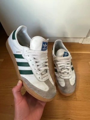 Adidas Samba OG white green gum stl 42 - Säljer nu dessa riktigt snygga Adidas Samba i storlek 42. De är vita med mörkgröna detaljer. De har tecken på användning men är fortfarande i fint skick. Vid frågor eller funderingar är det bara att höra av sig. Pris kan diskuteras.