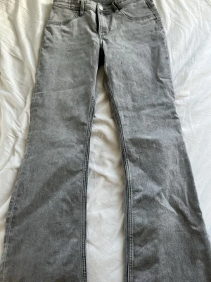 Grå bootcut jeans i denim - Snygga grå bootcut jeans i klassisk denim med fem fickor och normalhög midja. Jeansen har en lätt utsvängd passform nertill och stilrena sömmar. Perfekta för dig som gillar en avslappnad men trendig look.