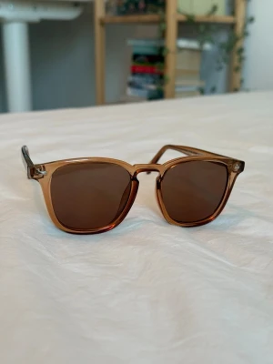 Samsøe solglasögon  - Snygga solbrillor från Samsøe med fyrkantiga bruna bågar i transparent plast och mörkbruna glas. Perfekt när det är soligt och när man vill lägga till en snygg touch på outfiten! Priset kan såklart diskuteras!