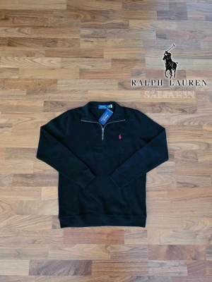 Svart Ralph Lauren Quarter Zip - 🖤 Ralph Lauren Quarter Zip – Svart | Storlek S 🖤  Exklusiv Ralph Lauren quarter zip i svart, perfekt för vardag och uppklätt. Tillverkad i mjuk bomull för komfort hela dagen. Klassisk lång ärm med ribbad fåll och ärmslut, samt rosa Ralph Lauren-logga på bröstet. Quarter zip-krage kan bäras uppvikt eller nedvikt. Tagg avklippt. Nyskick.  ✨ Detaljer: S, svart, mjuk bomull, ribbade detaljer, ikonisk logga.  📦 Snabb leverans – kontakta vid frågor.