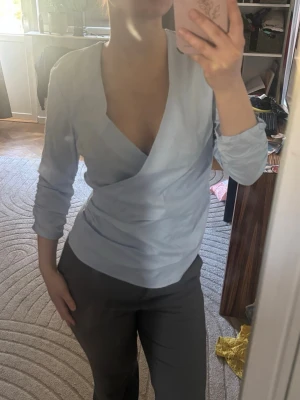 Snyggaste sommarblusen❤️ - Snygg ljusblå omlottblus med djup v-ringning och trekvartsärm. Blusen har en figurnära passform och är tillverkad i ett mjukt, lätt material som ger en stilren look. Perfekt att matcha med både jeans och kostymbyxor. Passar även S ( jag på bild är S)