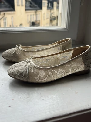 Spetsballerinor från Tamaris - Snygga ballerinaskor från Tamaris i ljusbeige spets med fina blommönster och liten rosett framtill. Skorna har rund tå och låg klack, bra skick, pris kan diskuteras.