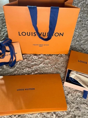 Louis Vuitton monogram armband - Snyggt armband från Louis Vuitton i klassiskt brunt monogrammönster med guldfärgat spänne. Tillverkat i belagt canvas med insida av kalvskinn. Kommer med originalpåse och ask säljer därav att jag inte använt armbandet mer än en gång nypris-2800kr
