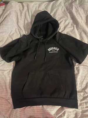 Svart hoodie från Hoodrich - Svart hoodie med långa ärmar från Hoodrich. Tryckt vit logga på bröstet, stor huva med snören storlek L funkar som M också knappt använd , bra skick 
