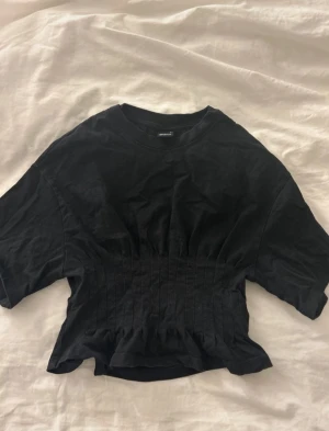 Svart topp från Gina Tricot - Säljer en svart topp från Gina Tricot med markerad midja och korta ärmar. Jättefin till sommaren och i jättebra skick!❣️ Ksriv om ni undrar nått eller vill ha fler bilder🥰