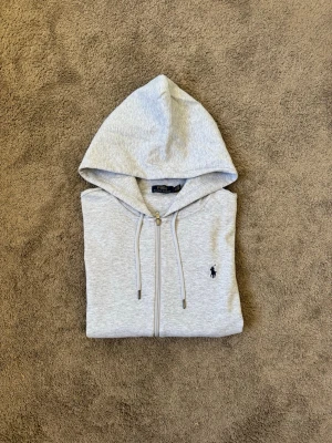 Ljusgrå hoodie från Polo Ralph Lauren - Hej ! Säljer nu denna gråa Ralph Lauren koftan. Endast testad, storlek S och passar för lite kyligare dagar. Vid frågor eller funderingar tveka inte på att höra av dig mvh 47 😁