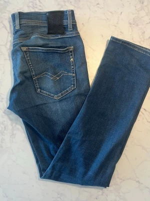 Blå raka jeans från Replay - Snygga blå jeans från Replay med raka ben och klassisk femficksdesign. Jeansen har en bakficka med dekorativ söm och Replay-logga. Tillverkade i mjukt denimtyg som ger en skön passform. Perfekta för en avslappnad och trendig look.