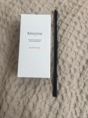 Kérastase Nutritive doftspridare - Säljer en Kérastase Nutritive doftspridare med tillhörande svarta pinnar. Flaskan är genomskinlig med räfflad yta och svart kork. Kommer i en vit kartong med stilren design. Perfekt för att ge hemmet en fräsch och lyxig doft.
