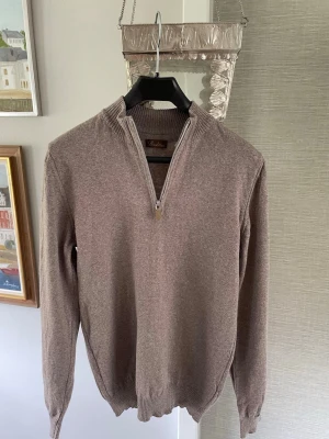 Beige/Grå half zip från Stenströms - Beige/Grå stickad half zip från Stenströms med ribbade muddar. Tröjan är gjord i 100% merino ull av väldigt hög kvalitet. Den är i bra skick överlag, en lagning har gjorts på vänster ärm (se bild 5 och 6). Det är inget som syns vid användning utan bara vid närmare titt.
