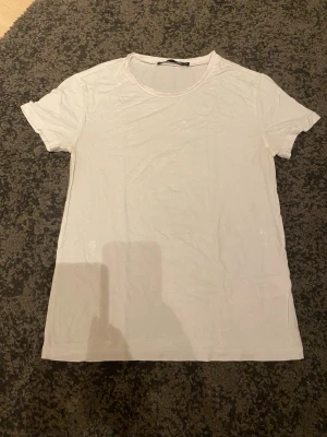 Vit basic t-shirt från 157 - En klassisk vit t-shirt från 157 med rund halsringning och korta ärmar. Tillverkad i mjuk bomull som är skön mot huden. Perfekt att matcha med jeans eller shorts för en enkel och clean look.