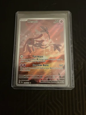Pokémonkort Mesprit holo - Säljer ett Pokémonkort med Mesprit-motiv, holografisk yta och fina rosa och orange färgdetaljer. Kortet är inplastat i ett skyddsfodral. Perfekt för samlare eller Pokémonfans som vill utöka sin samling.