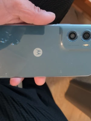 Motorola moto g06 Android smartphone blå - Snygg Motorola Android-telefon i blått med stilren design och två bakre kameror. Baksidan är i glas med Motorola-loggan i mitten. Kameramodulen är upphöjd och har en modern look. Perfekt för dig som vill ha en cool och pålitlig mobil...köpt den 19april  för 1350kr laddare medföljer den har 2st skärm skydd på