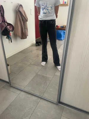 Svarta bootcut jeans med hög midja - Säljer ett par svarta bootcut jeans med hög midja och klassiska fem fickor. Jeansen har en snygg passform som sitter tight upptill och släpper ut vid benen. Perfekta till en trendig vardagslook och passar till det mesta i garderoben.