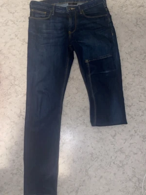 Mörkblå raka armani jeans  - Säljer ett par mörkblå jeans med raka ben och kontrastsömmar. Jeansen har en extra ficka på ena benet och klassiska bakfickor med dekorativ söm. Materialet är denim i bomull och passformen är avslappnad.