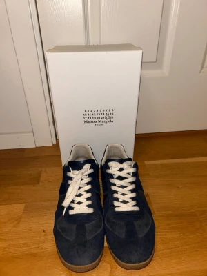 Blå Maison Margiela sneakers i mocka - Snygga stilrena Maison marginela skor i mocka. Säljer pågrund av att fem inte används. Storlek 42,5. Näst intill nyskick då skorna bara används fåtal gånger.