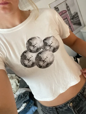 Vit t-shirt med discokulor - Vit t-shirt i bomull med tryck av fyra discokulor på bröstet. Bara att kontakta vid frågor!