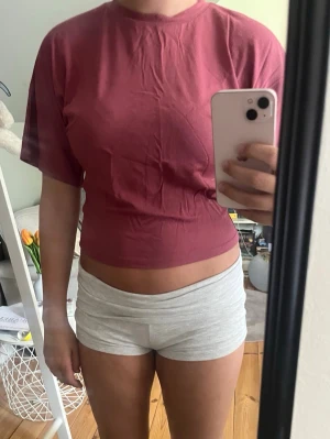 Croppad mörkrosa t-shirt - En enkel croppad t-shirt i mörkrosa färg med rund halsringning och korta ärmar. Tillverkad i mjukt bomullsmaterial som känns skönt mot huden. Perfekt till jeans eller shorts för en avslappnad look. Liten fläck på ryggen