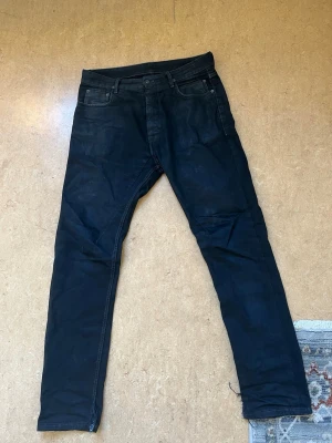 Rick owens drkshdw torrence cut size 33 - Säljer ett par svarta slim fit jeans med klassisk femficksdesign och dragkedja. Jeansen har kontrastsömmar och är tillverkade i ett stretchigt denimtyg som ger en skön passform. Perfekta för dig som gillar en stilren och enkel look.