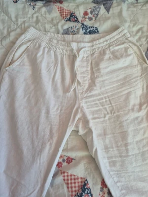 Cubus vita linnebyxor - Säljer ett par vita linnebyxor med avslappnad passform och resår i midjan. Byxorna har sidfickor fram och två passpoalfickor bak. Perfekta för en chill och stilren look under varma dagar. Materialet är luftigt linne som känns svalt och skönt.
