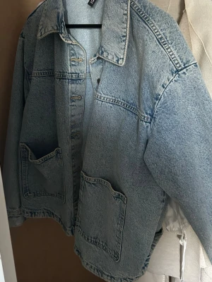 Oversized ljusblå jeansjacka - Säljer en oversized ljusblå jeansjacka med stora framfickor och klassisk krage. Jackan har en avslappnad passform och tydliga sömmar som ger en cool vintagekänsla. Perfekt att slänga över en hoodie eller t-shirt för en casual look.